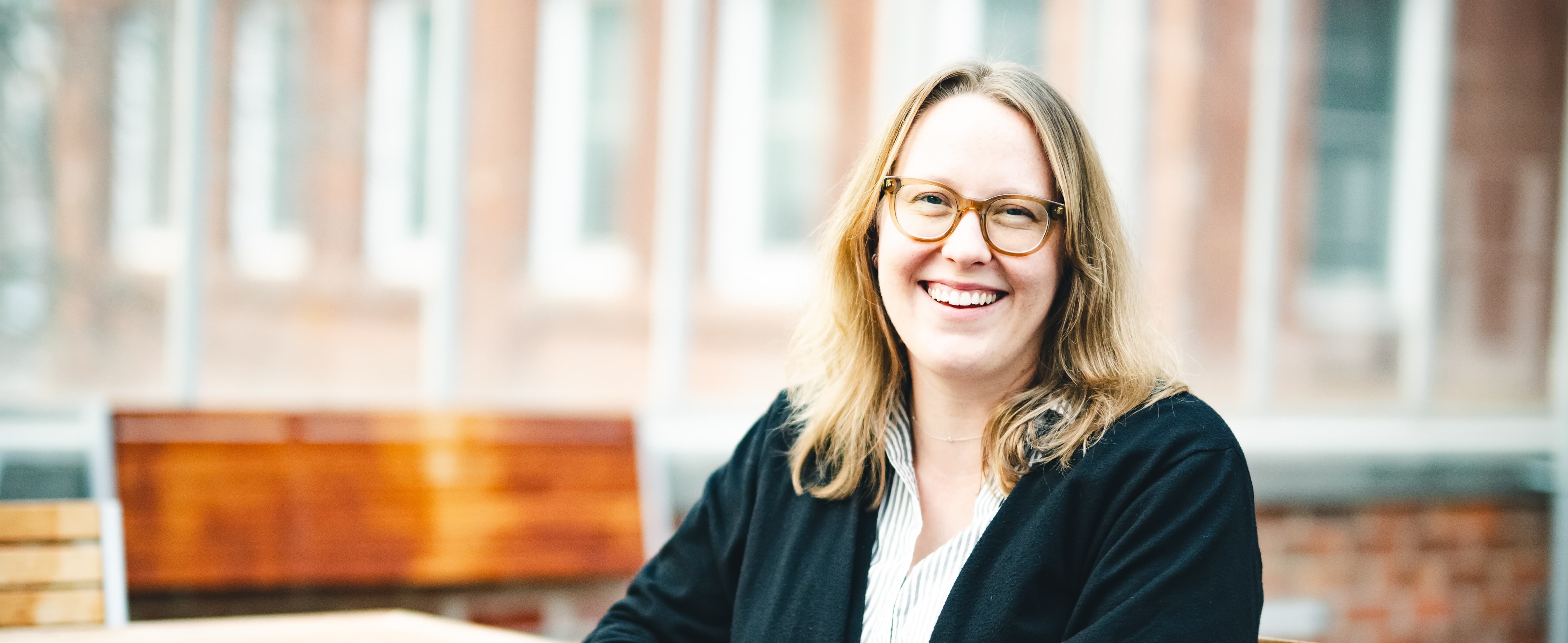 Amy Johnson sits in a greenhouse and smiles for a portrait.